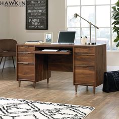 a wooden desk with a laptop on it in front of a window and a chair