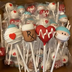 a box filled with lots of cake pops covered in frosting and decorated like doctors