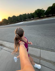 a woman in a purple dress is riding a skateboard down the street at sunset