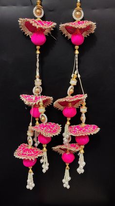 two pairs of pink and gold earrings hanging from the side on a black surface with white beads