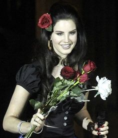 a woman in a black dress holding roses