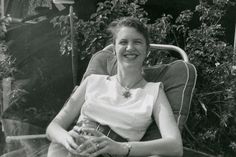 a woman sitting in a chair smiling at the camera