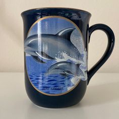 two dolphins jumping out of the water on a blue coffee mug with gold trimmings