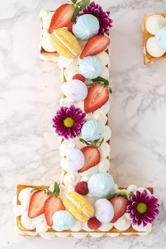 a letter made out of cake and decorated with flowers on the top, sitting on a marble surface