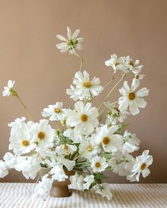 a vase filled with lots of white flowers on top of a checkered table cloth