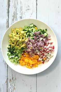 a white bowl filled with chopped vegetables on top of a wooden table