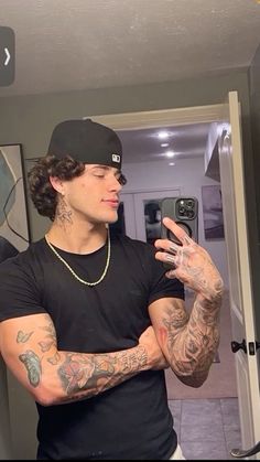 a man taking a selfie with his cell phone in front of him and tattoos on his arms