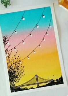 an image of a card with string lights and a bridge in the background at sunset