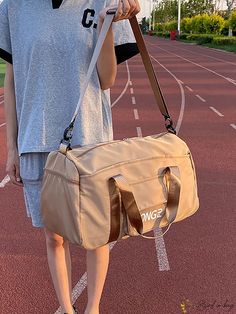 a woman is holding a bag on a track