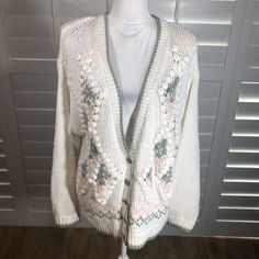 a white cardigan sweater with flowers on it