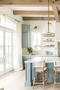 a kitchen with blue cabinets and white counter tops, two bar stools in front of the island