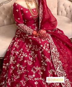 a woman in a red wedding dress sitting on a white couch with her hand on her hip