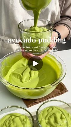 a person pouring green liquid into three bowls with spoons in them and the words avocado pudding on top