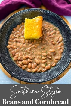 a black bowl filled with beans and a piece of bread