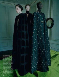 two women in black dresses standing next to each other on a green carpeted floor