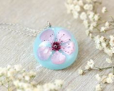 This cherry flower necklace is made from a real cherry flower picked up from the place where I live. A unique sakura necklace as the most unique birthday gift idea for women. In general, a cherry flower necklace (japanese flower necklace) is an outstanding full of significance complement for you. This sakura blossom necklace is part of my pale pink jewelry. The hypoallergenic stainless steel and the high-gloss crystalline resin gives this cherry flower necklace a precious and enamelled look. Use Flower Necklace With Pressed Flowers For Birthday, Pink Flower Necklace For Birthday Gift, Birthday Flower Pendant Necklace With Pressed Flowers, Delicate Blossom-colored Jewelry For Gifts, Delicate Blossom Colored Jewelry As Gift, Delicate Blossom Jewelry Gift, Spring Flower Jewelry Gift, Spring Flower Decorated Jewelry Gift, Handmade Pink Necklace For Mom