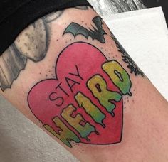 a tattoo with the word stay weird on it's arm and an image of a heart