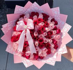 a bouquet of red and pink roses is being held by someone