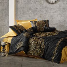 a black and yellow comforter set on a bed with a clock in the background