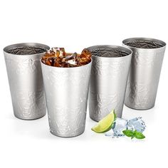 four silver metal cups with ice and limes on the side next to each other