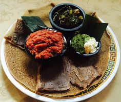 a plate with meat, vegetables and sauces on it