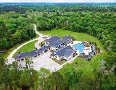 an aerial view of a large home surrounded by trees and grass with a pool in the middle