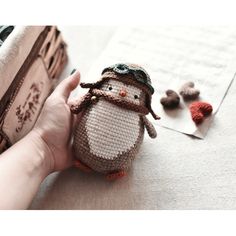 a person holding a small stuffed animal on top of a white table next to a book