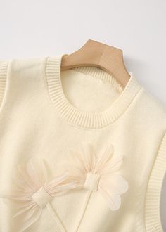 a white sweater with a flower on the front and a pink bow at the back