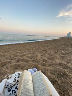 an open book sitting on top of a sandy beach