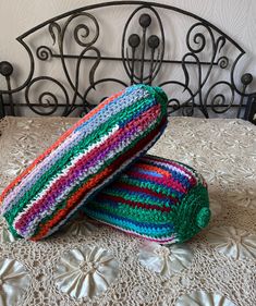 two crocheted pillows sitting on top of a bed next to an iron headboard