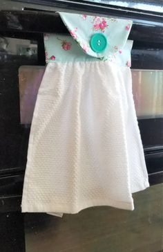 a white dress hanging from the side of an oven with flowers and green buttons on it