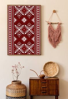 a red and white artwork hangs on the wall next to a small table with two baskets