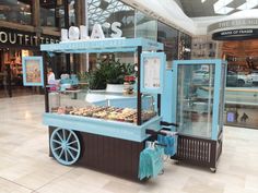 a blue and black cart with donuts on it in a store filled with people