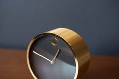 a gold clock sitting on top of a wooden table