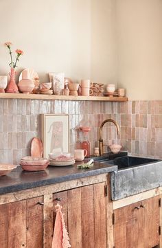 the kitchen counter is covered with pink dishes and cups, including one that has flowers on it