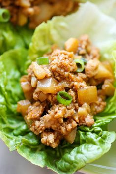 two lettuce wraps with meat and vegetables on top, sitting on a plate