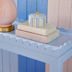 two books are stacked on top of each other next to a pink and blue vase