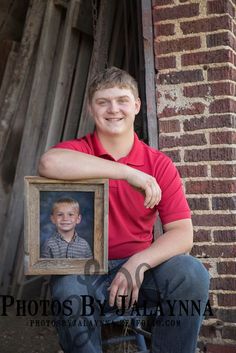 a young man sitting on a chair holding a framed photo