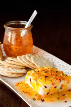 an appetizer is served on a plate with crackers and honey in the background