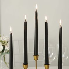 four black candles with gold holders on a table