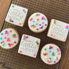 four decorated cookies on a cooling rack with happy birthday sandra written in frosting