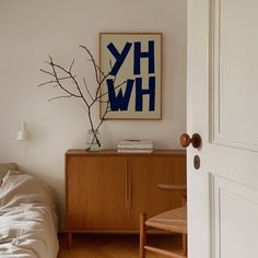 a bedroom scene with focus on the bed and dresser in the foreground, there is a framed hw poster above it