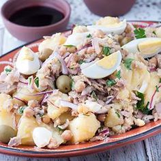 a plate filled with potatoes and meat on top of a table next to a cup of coffee