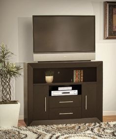 a flat screen tv sitting on top of a wooden entertainment center next to a potted plant