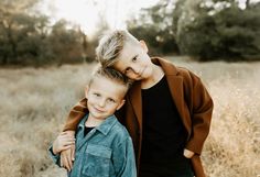 two young boys standing next to each other in a field