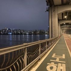 a bike path on the side of a bridge with water and buildings in the background