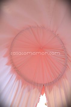 the inside of a pink and white umbrella with tassels on it's sides