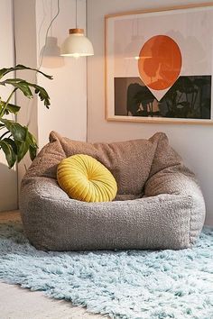 a grey bean bag chair sitting on top of a rug next to a potted plant