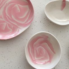 three pink and white bowls with spoons on the table next to each other,