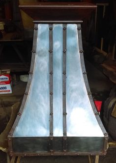 a large metal oven sitting on top of a piece of wood in a garage next to other items